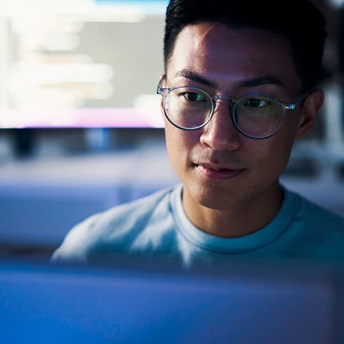 Man wearing glasses looking at laptop screen